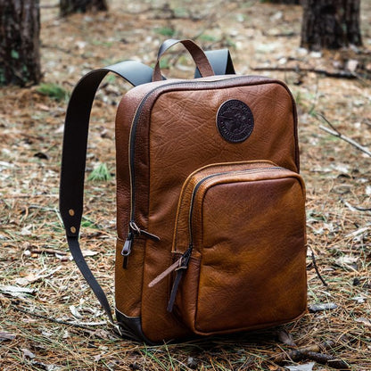 Brown leather backpack on a forest floor